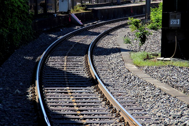 railroad tracks curving around the edge of a building to an unknown destination