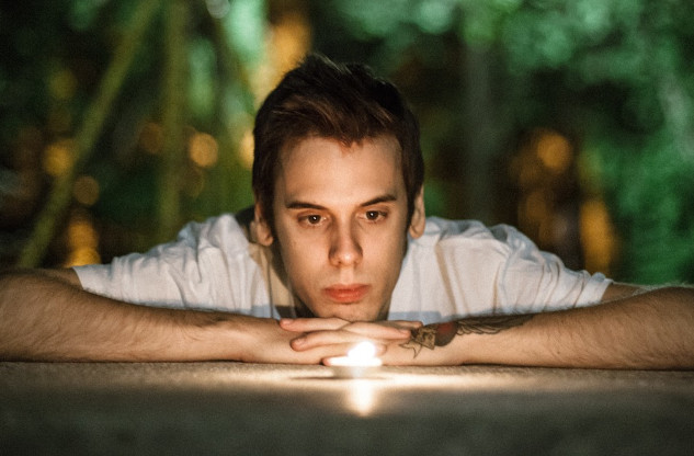 a young man laying down staring into a candle flame