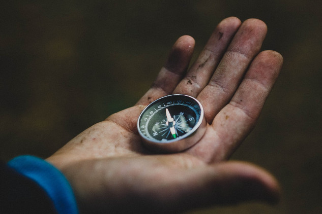 a man in a suit holding a compass in his open hand