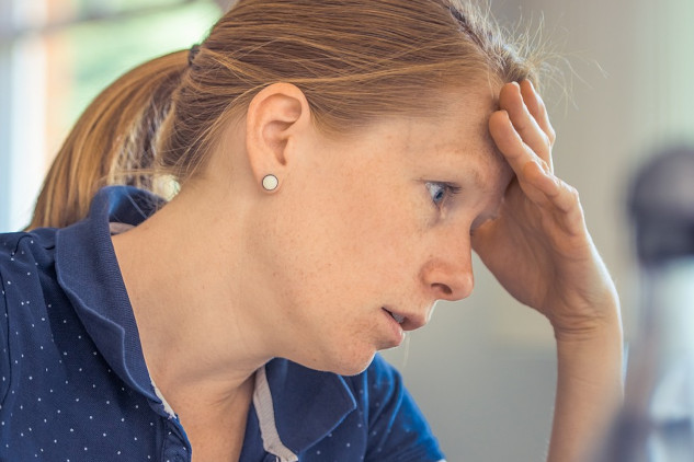 a woman in concentration resting her forehead on her hand