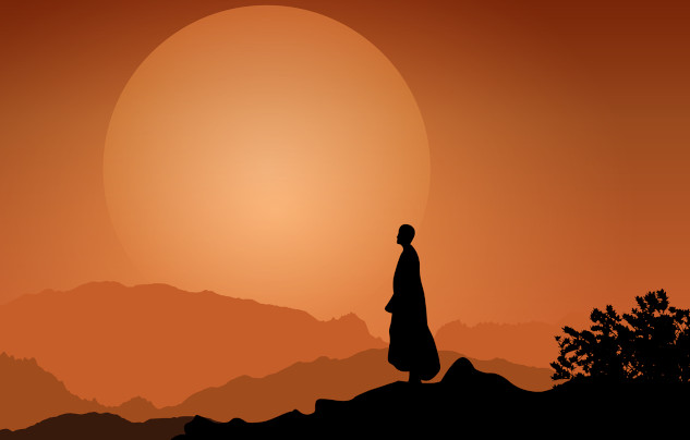 a monk standing peaceful in front of the setting sun