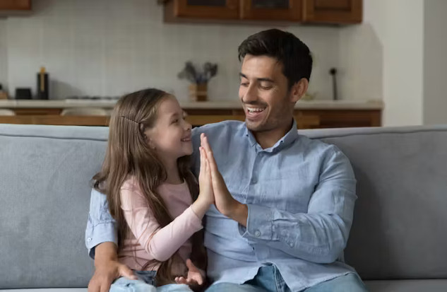 A warm, natural scene of a parent sitting down to the eye level of a young child