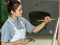 smiling woman paintbrush in hand working on a canvas