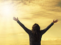 a person facing the sun with arms wide open to the sky