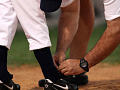 coach tying the shoe of a baseball player