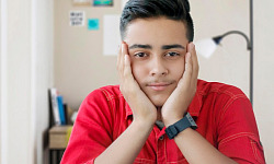 young man with his chin resting on his hands smiling peacefully