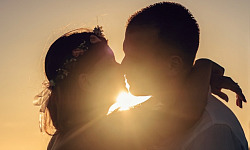 two people kissing with the light shining brightly behind them