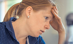 a woman in concentration resting her forehead on her hand