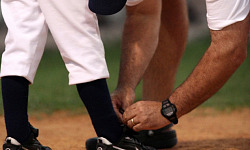 coach tying the shoe of a baseball player