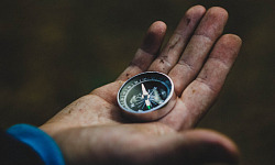 a man in a suit holding a compass in his open hand