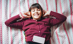 Child listening to an audiobook with headphones, illustrating enhanced imagination and intellectual development.