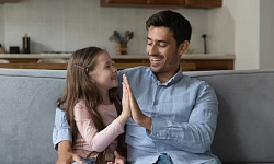 A warm, natural scene of a parent sitting down to the eye level of a young child