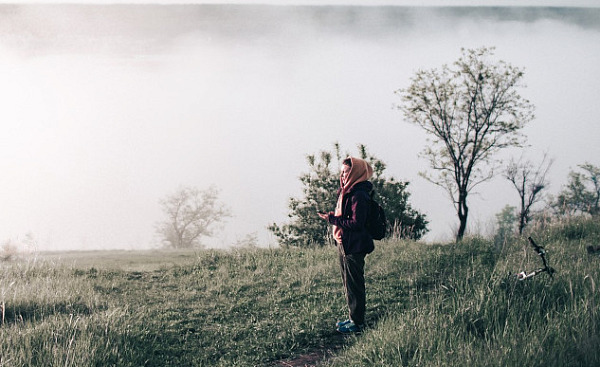 a woman wearing a scarf standing on a hillside