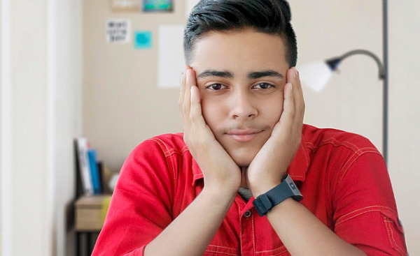 young man with his chin resting on his hands smiling peacefully