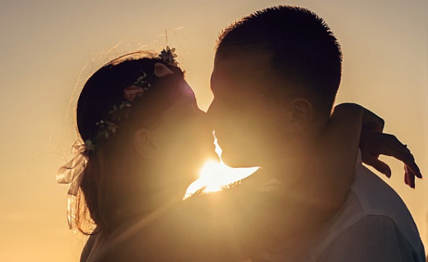 two people kissing with the light shining brightly behind them