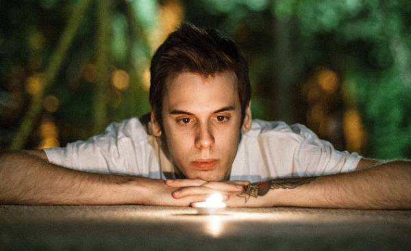 a young man laying down staring into a candle flame