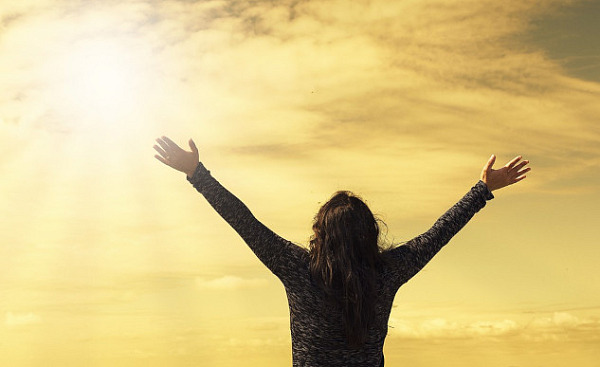 a person facing the sun with arms wide open to the sky