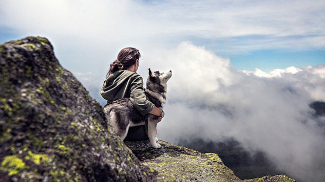 woman sitting outside with her arm around a husky dog