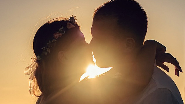 two people kissing with the light shining brightly behind them