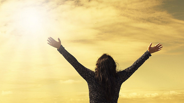 a person facing the sun with arms wide open to the sky