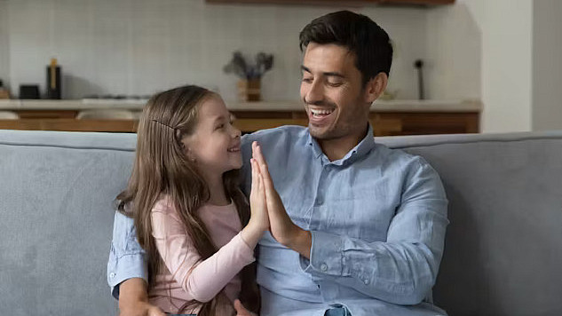 A warm, natural scene of a parent sitting down to the eye level of a young child