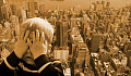 boy covering up his face as if afraid of the tall city landscape behind him