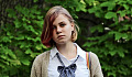 young teen with dyed-pink bangs looking sad outdoors