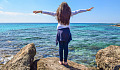 young girl with arms wide open in front of the ocean