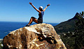 woman sitting on top of a mountain with arms stretched out in triumph