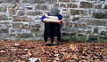 youth sitting alone outside with his head down on his arms