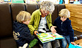 a grandmother reading to her two grandchildren