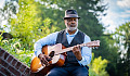 a man sitting on a brick fence and playing a guitar