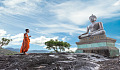 statue of buddha with a young monk standing in front